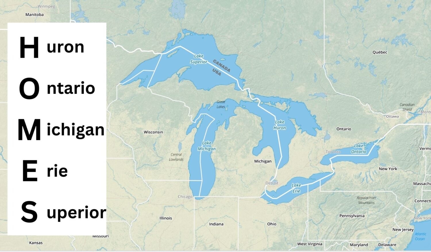 Shaded relief map showing the Great Lakes in blue and the surrounding areas in shades of green and yellow with the mnemonic "HOMES" in bold black letters.