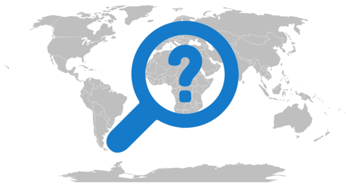 Grayscale map of the world with a question mark inside of a magnifying glass.