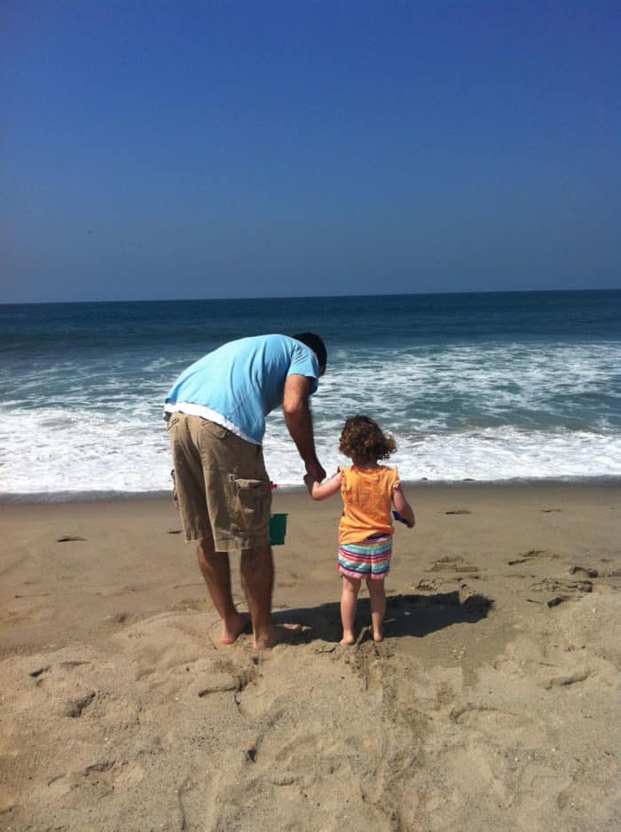 A father and daughter look out at the Pacific Ocean.