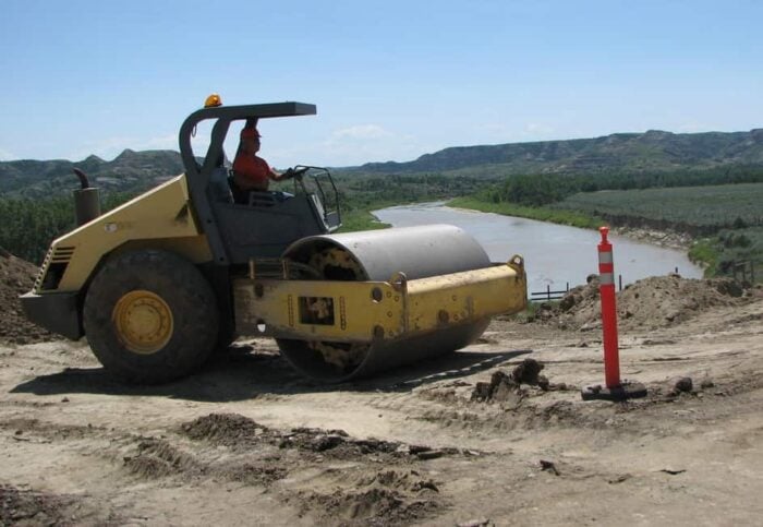 A construction worker driving a steamroller.