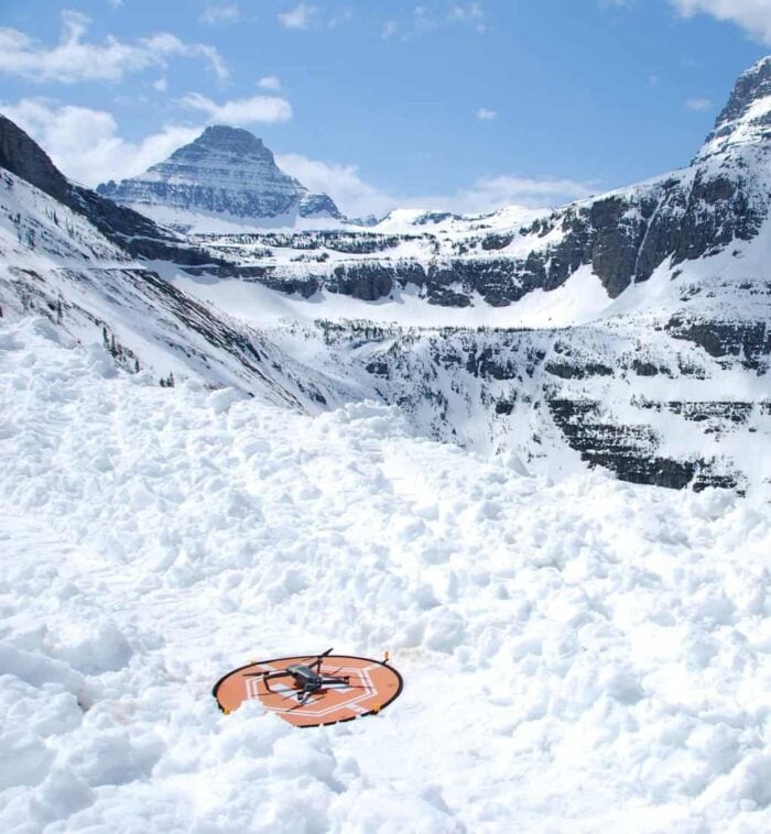 A drone sitting on top of snow in the mountains.