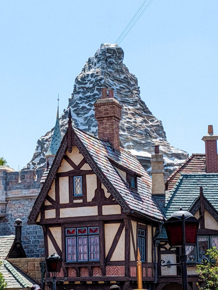 A replica of the Matterhorn mountain behind an alpine inspired building in Disneyland.