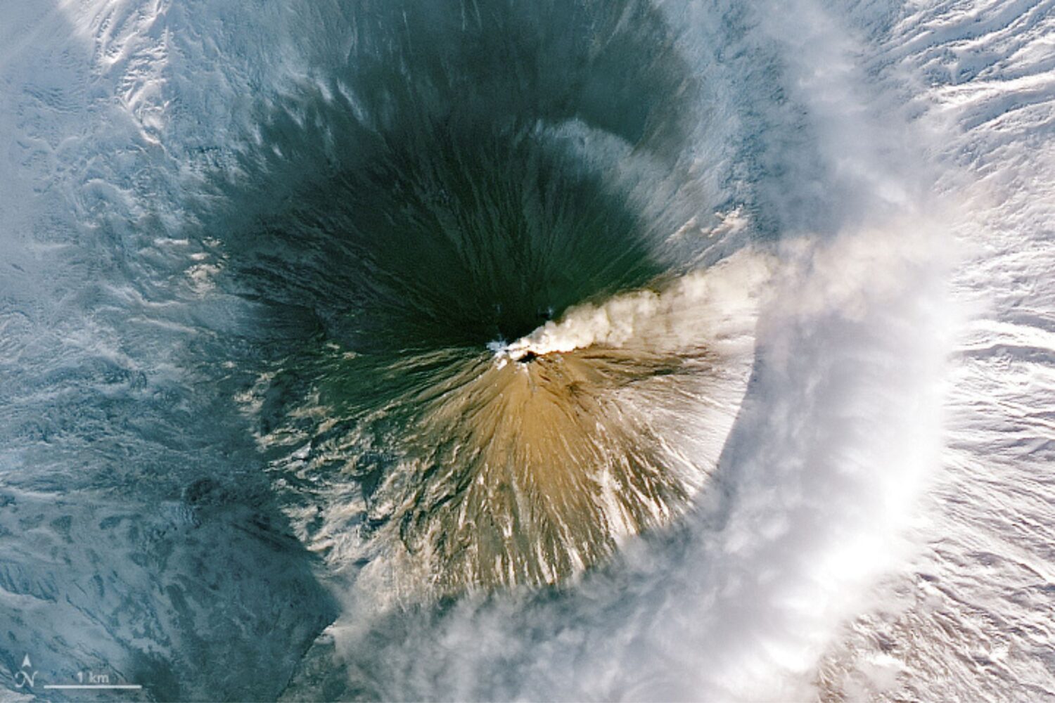 A closeup of Klyuchevskoy volcano erupting surrounded by a dusting of snow.