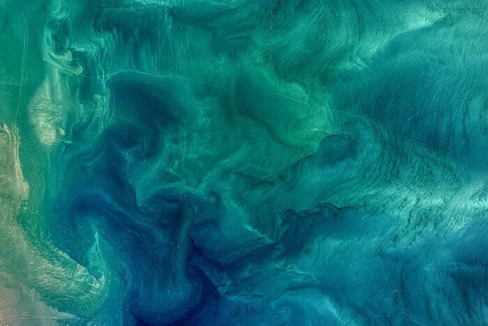 A satellite image of a section of the ocean showing swirling colors of blues and greens.